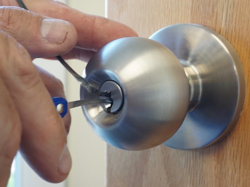 locksmith unlocking front door knob on a house with a pickset