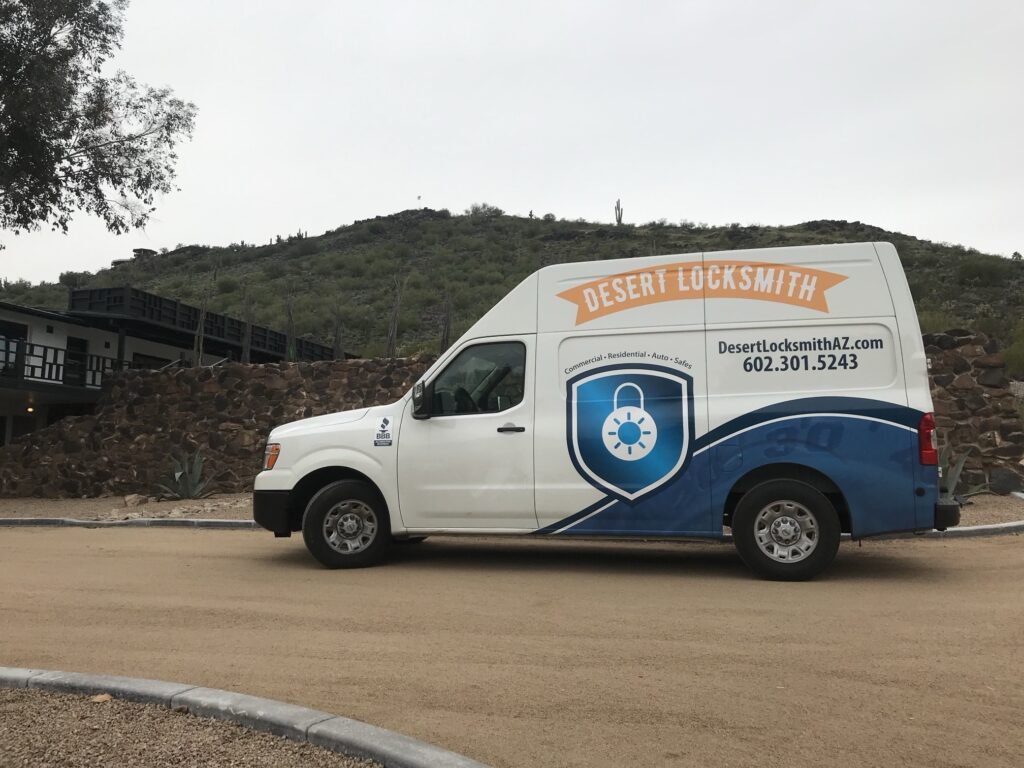 Desert Locksmith van parked in front of a rock wall and a desert hill with saguaro cactus
